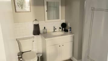 Een bad/douchecombinatie, een haardroger, handdoeken, zeep