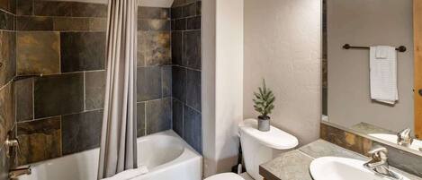 A bathroom with a bathtub, toilet, and sink.