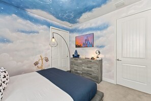 Une chambre avec une fresque représentant un ciel étoilé, un lit, une commode et une porte.