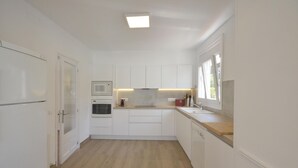 A modern kitchen with white cabinets, a microwave, oven, and a wooden countertop. - To rent house with private pool in Begur, center (Begur)