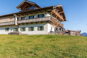 A traditional chalet with a balcony, a wooden staircase, and a stone foundation. - Holiday Apartment Talblick with Mountain View, Wi-Fi (Jachenau)