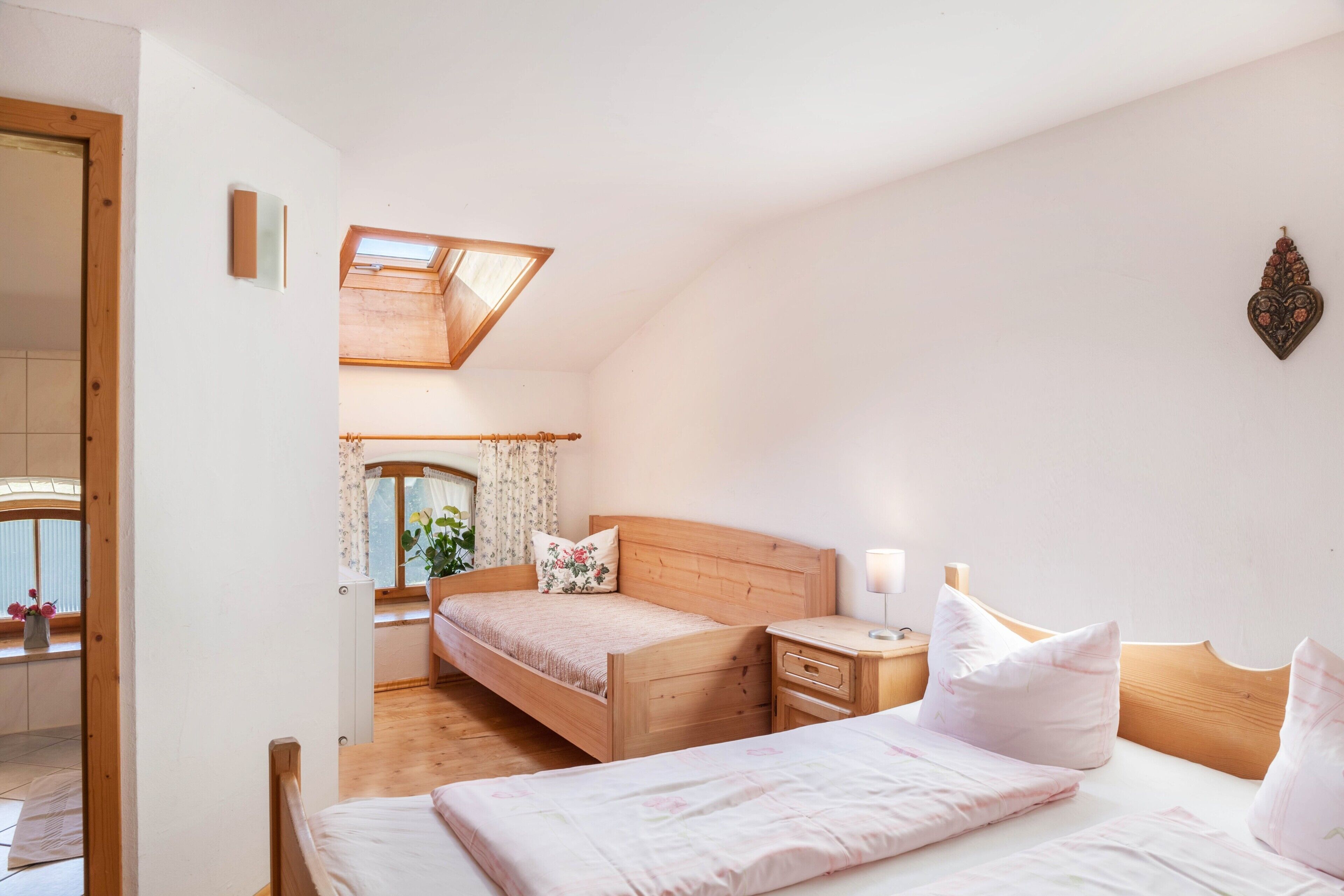 Ein Schlafzimmer mit Dachfenster, einem hölzernen Bett, einem Nachttisch und einem Beistelltisch.
