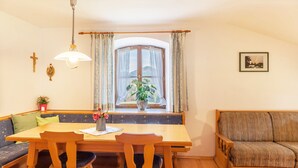 Een eetruimte met een houten tafel, twee stoelen, een bank en een raam met gordijnen.