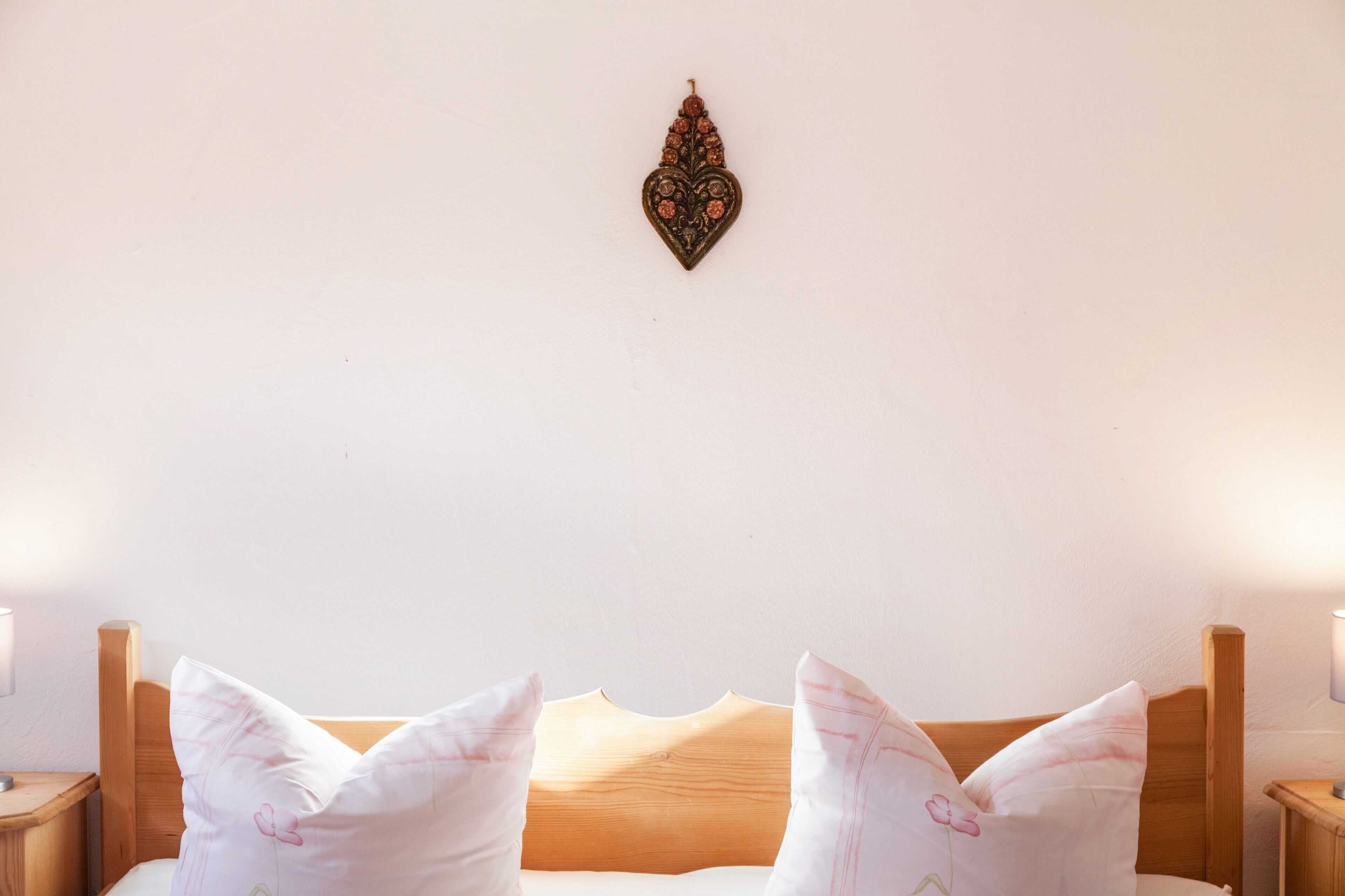 A bed with a wooden headboard, two pillows, and a wall-mounted decorative item.