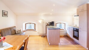 Een moderne keuken met een eetgedeelte, houten keukenkastjes, een centraal eiland en een inbouwoven.