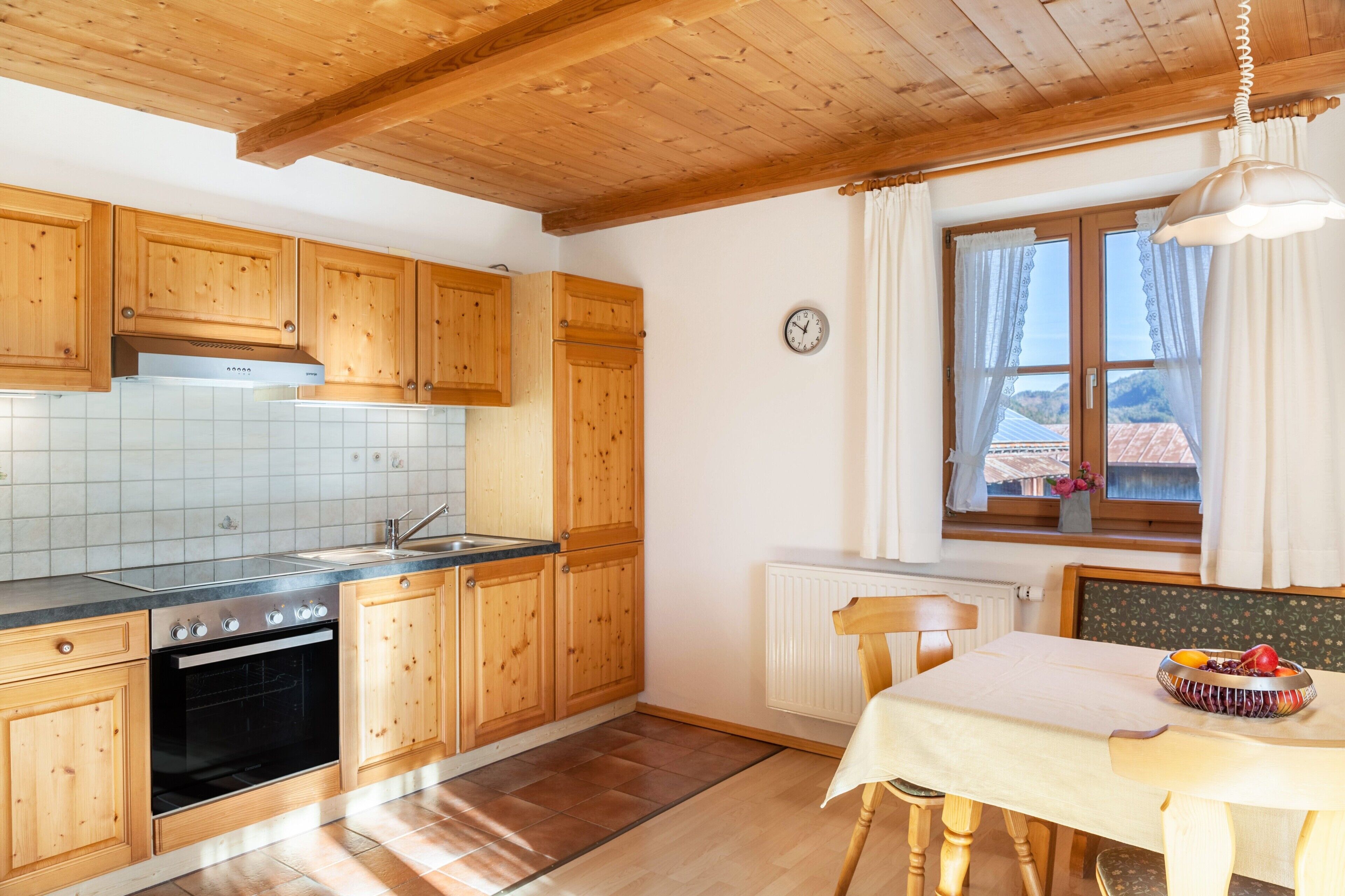 Una cocina con armarios de madera, estufa, lavaplatos y un comedor con mesa y sillas.