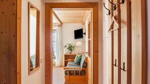 A wooden hallway with a sofa, a television, and a plant. - Holiday Apartment Guffertblick with Mountain View, Wi-Fi (Jachenau)