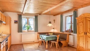 Ein Holzinterieur mit Esstisch, Stühlen, einer Bank, einem Heizkörper und einem Holzschrank.