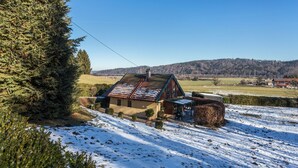 Een huis met een schuin dak, omgeven door een met sneeuw bedekte grond, met een heldere lucht en verre heuvels.