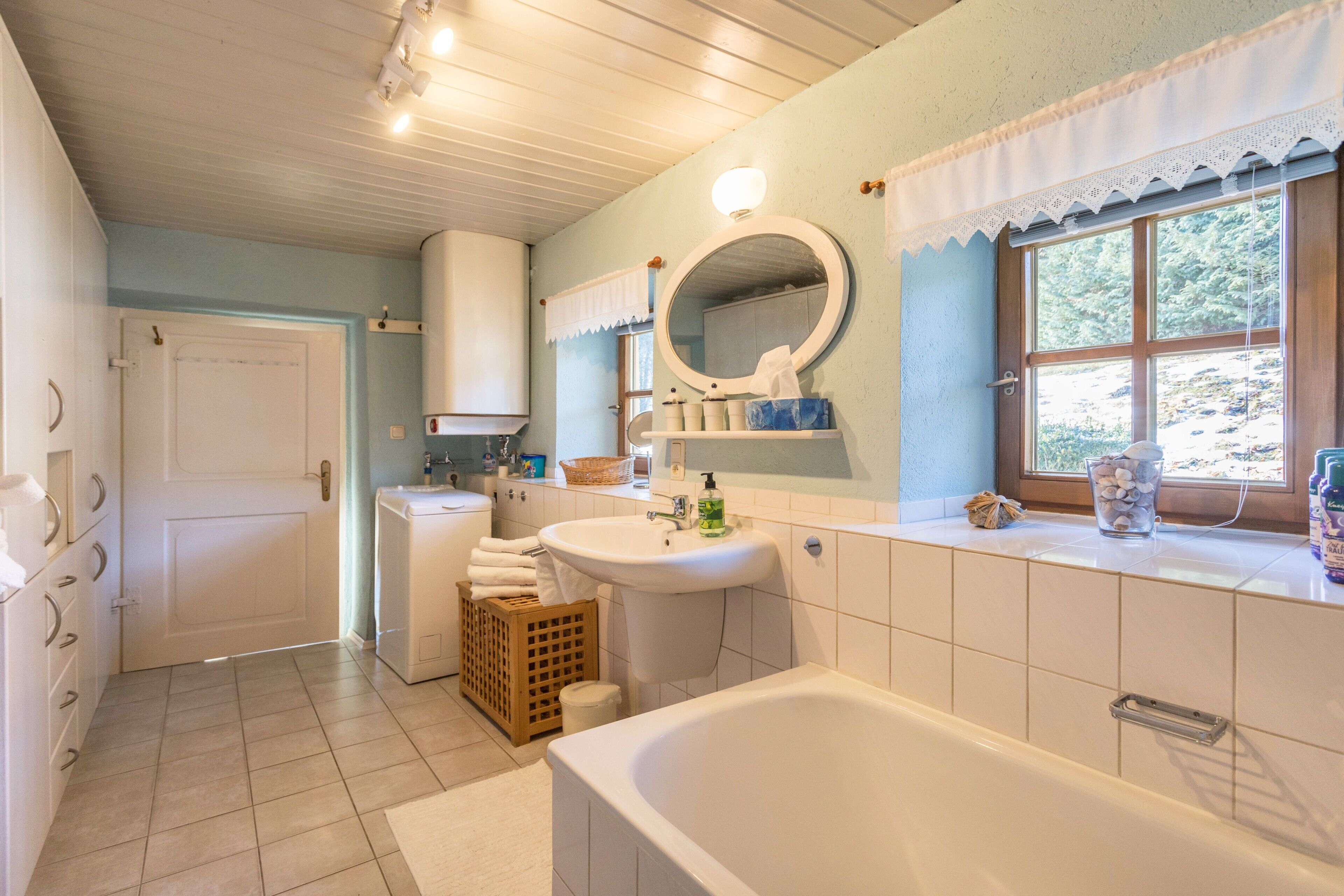 Ein Badezimmer mit Badewanne, Waschbecken, Spiegel und Fenster mit Blick.