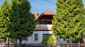 A two-story house with a stone facade, wooden roof, and a wooden fence in front. - Vacation home Tamas by Interhome (Balatonoszod)