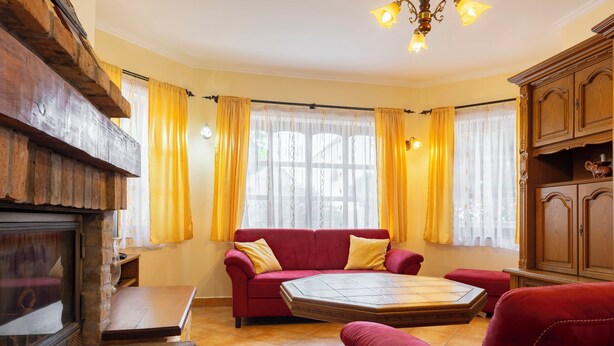 A cozy living room with a fireplace, red sofa, and yellow curtains. - Vacation home Tamas by Interhome (Balatonoszod)