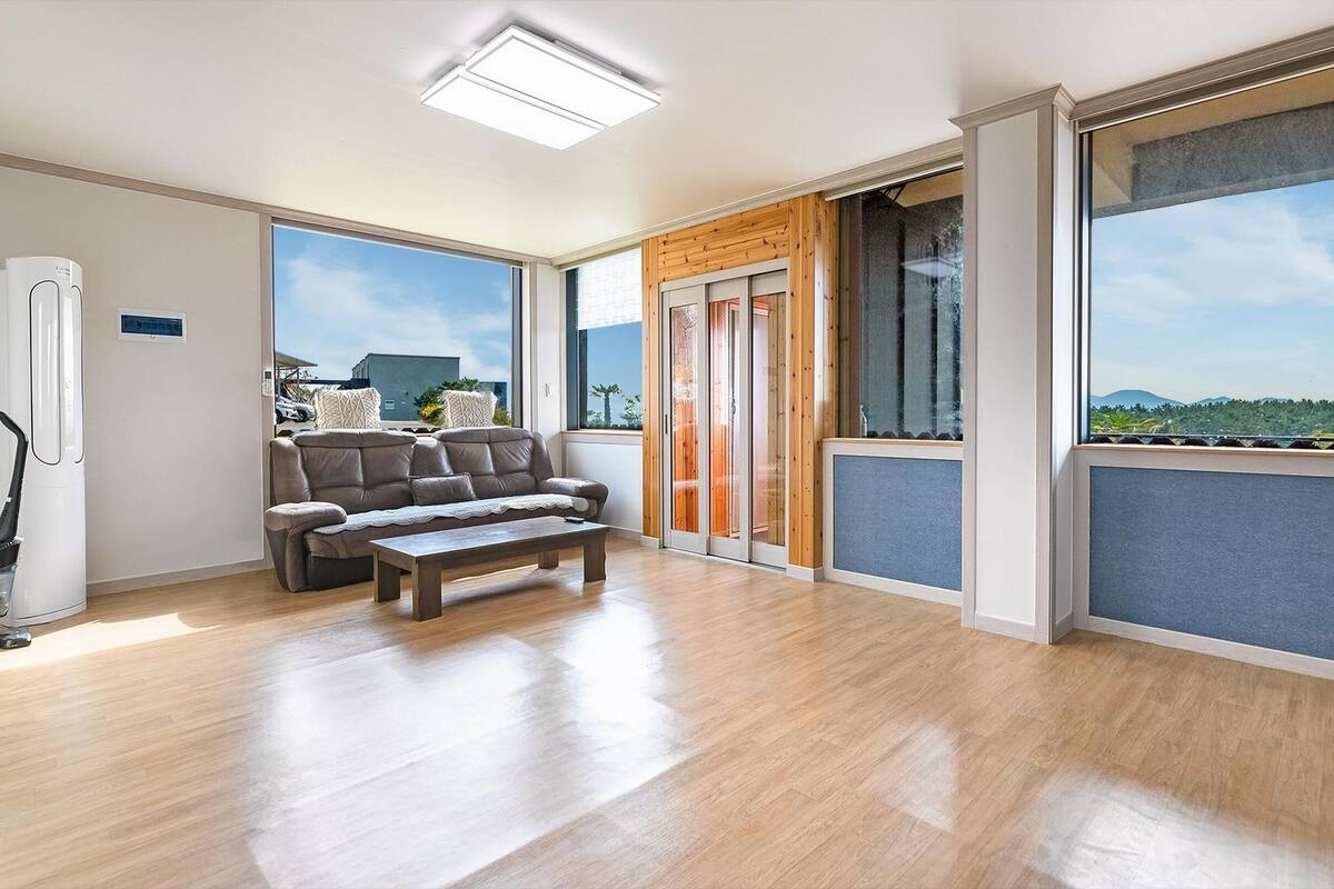 Een ruim balkon met een houten vloer, een bank en een bijzettafeltje.