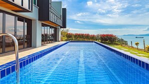 A modern swimming pool with a view of the sea and mountains.