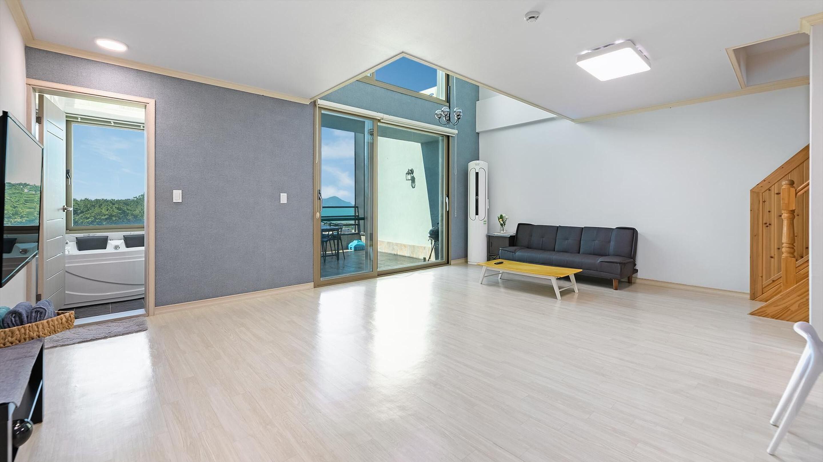 Un vaste espace de vie comprenant un canapé, une table basse et une vue sur une terrasse extérieure, accessible par une porte vitrée.