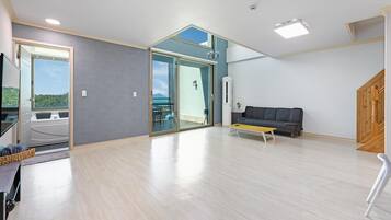 Un vaste espace de vie comprenant un canapé, une table basse et une vue sur une terrasse extérieure, accessible par une porte vitrée.