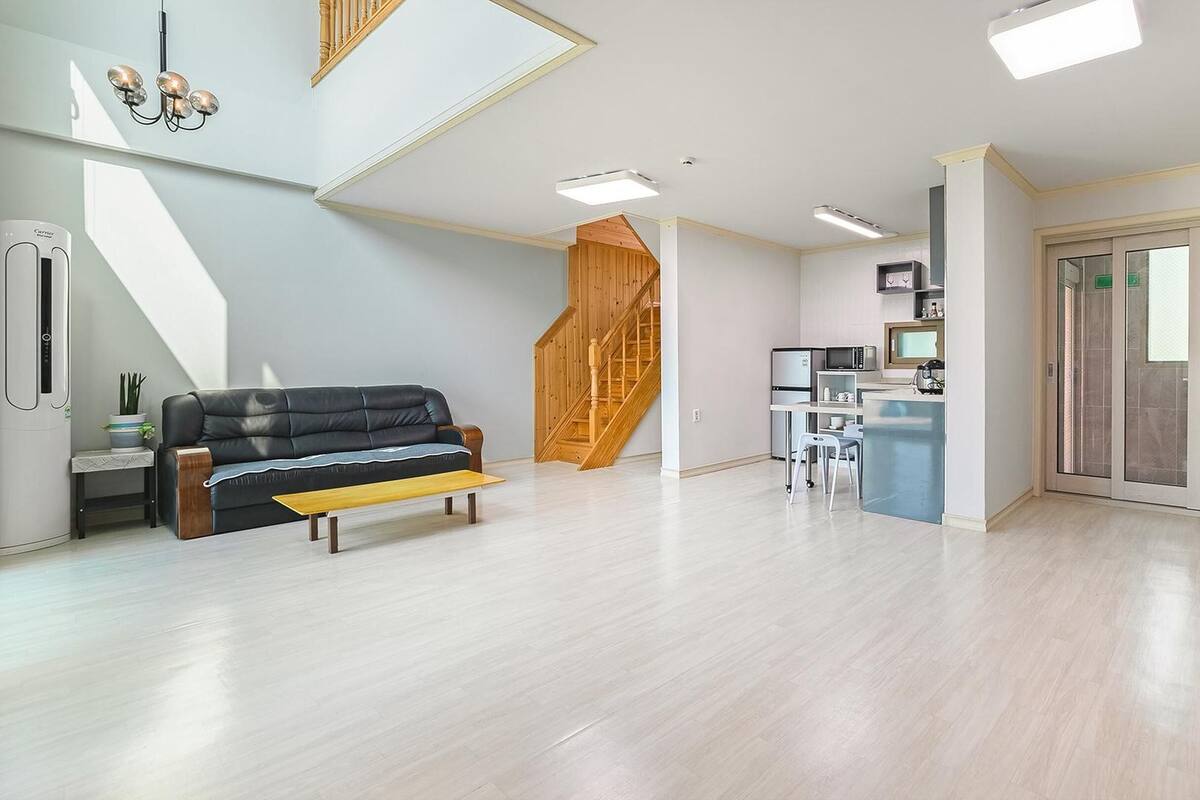 Een moderne woonruimte met een bank, een eettafel, een keukenhoek en een glazen schuifdeur naar een balkon.