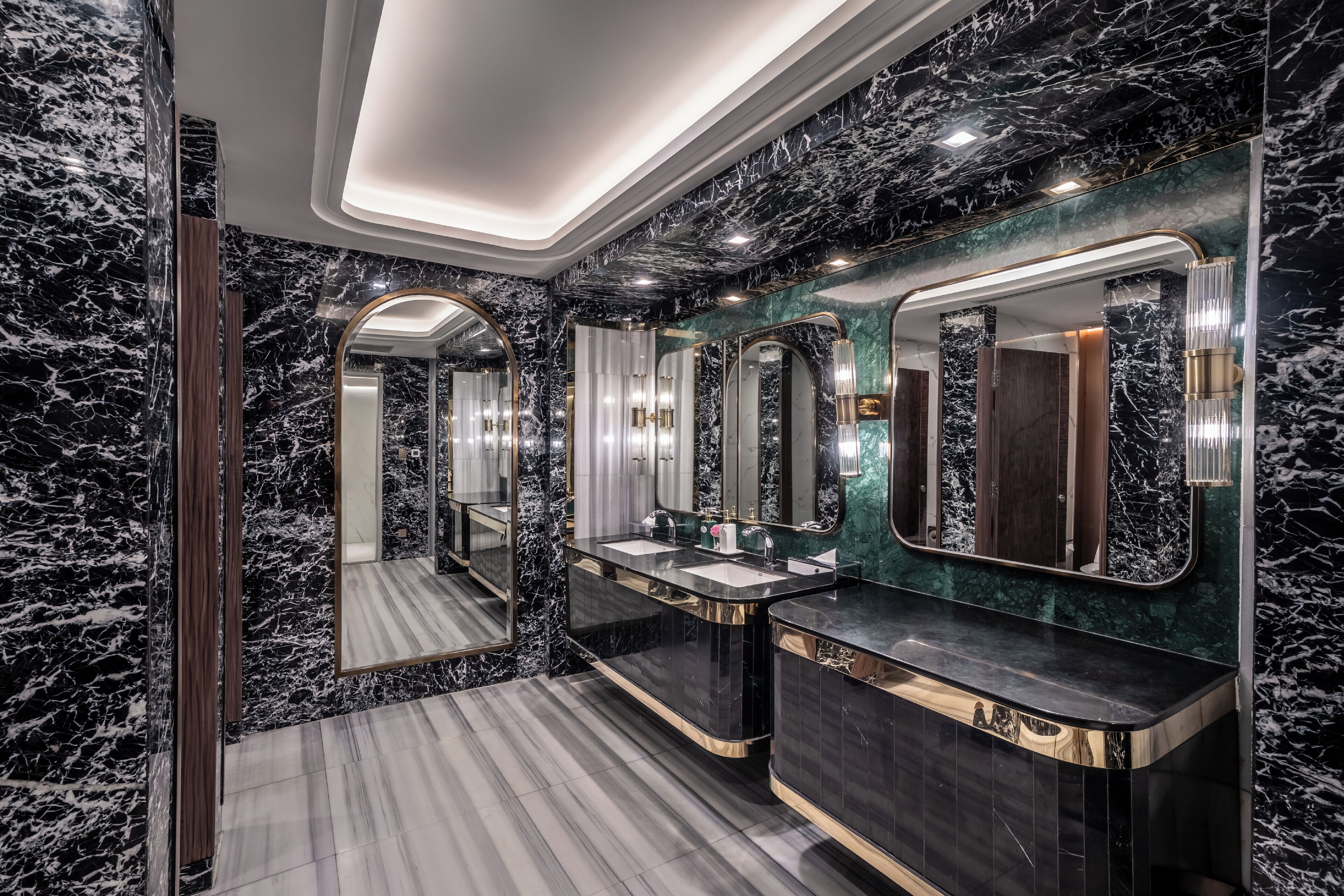 Ein luxuriöses Badezimmer mit Marmorwänden und -böden, zwei Waschbecken und modernen Leuchten.