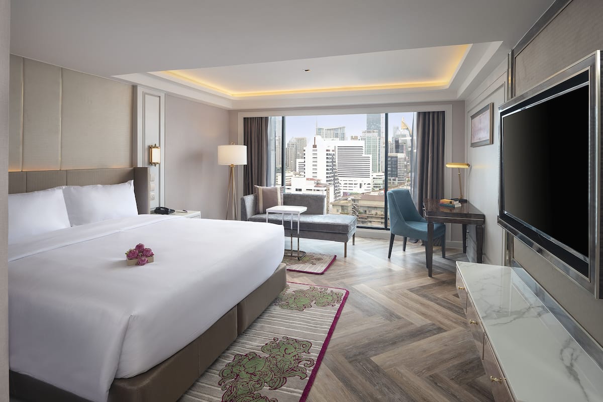 Una habitación de hotel moderna con una cama grande, un escritorio, una silla y un televisor.
