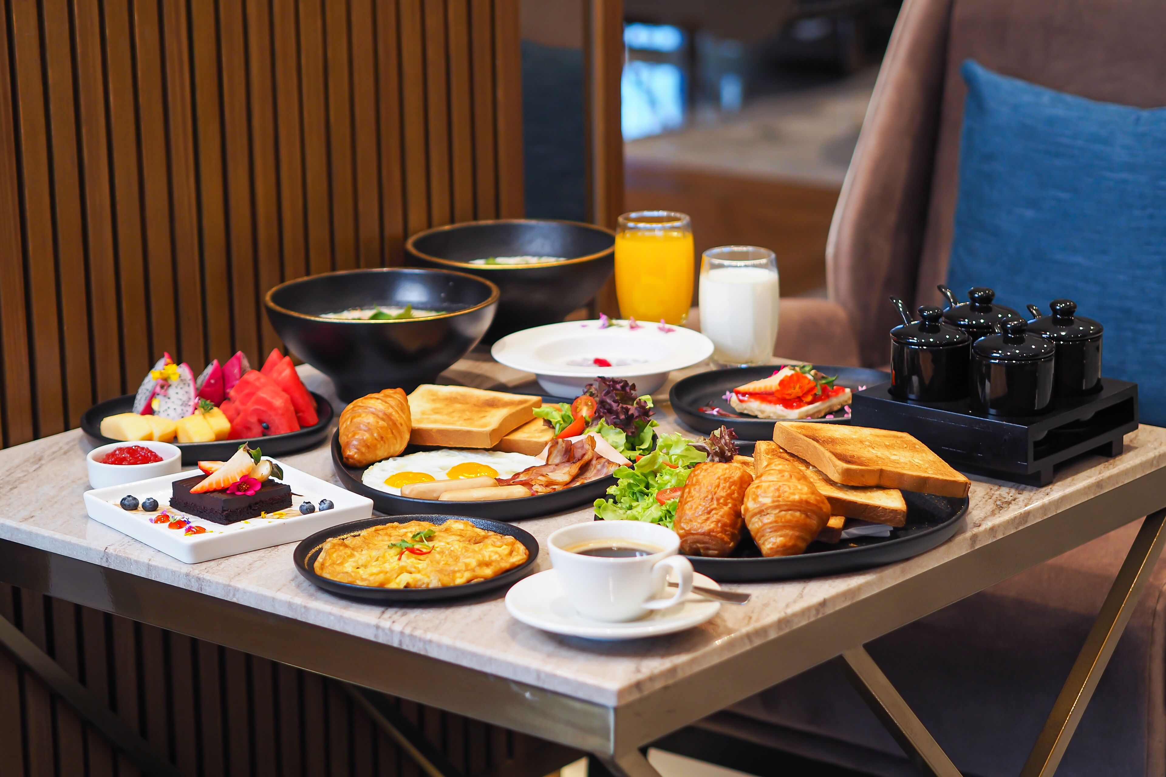 Un buffet de petit-déjeuner proposant une variété de plats, notamment des fruits, des viennoiseries et des boissons.