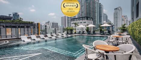 Una piscina al aire libre, sombrillas, sillones reclinables de piscina