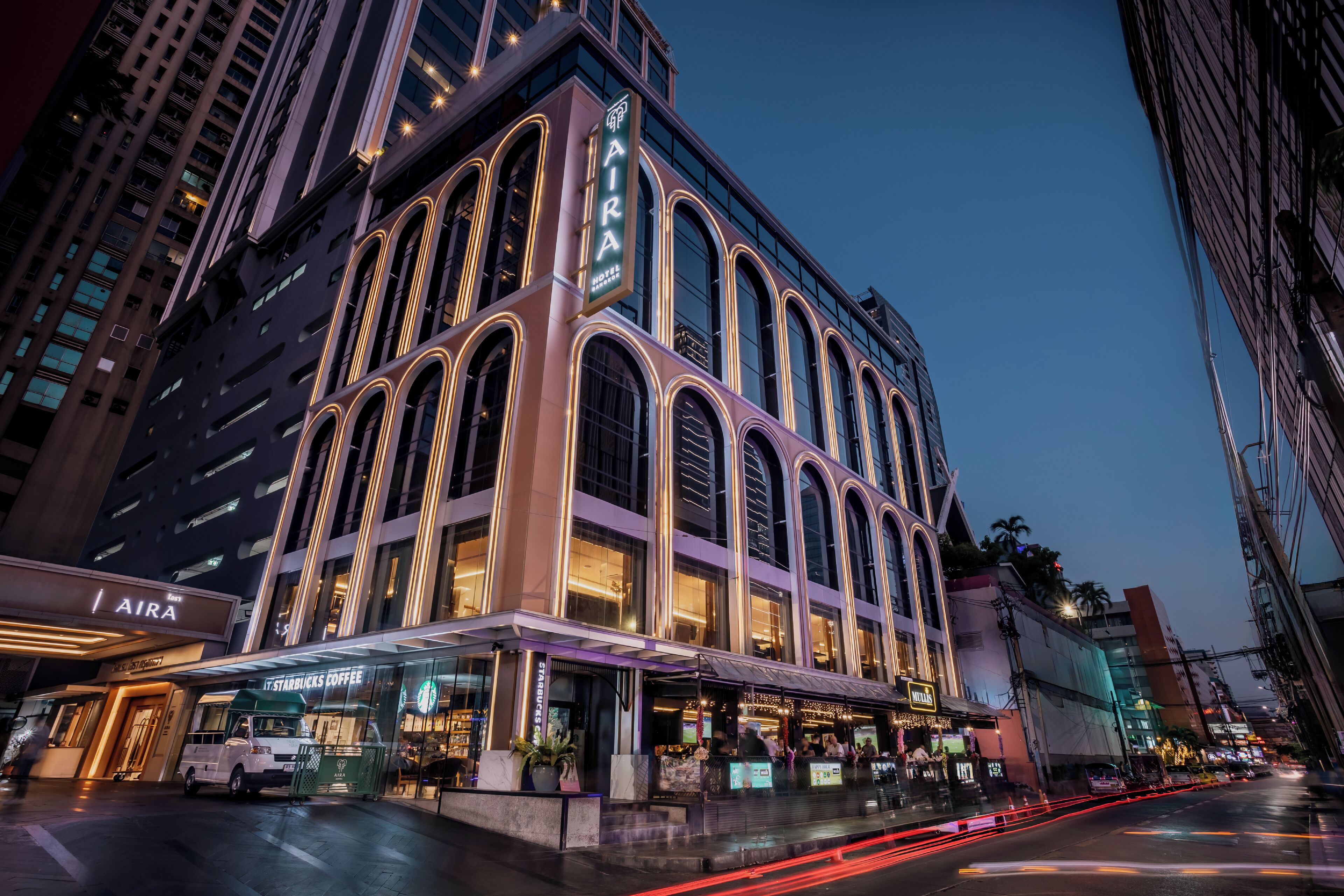A multi-story building with a prominent 'AIRA' sign, featuring a Starbucks Coffee shop on the ground floor.