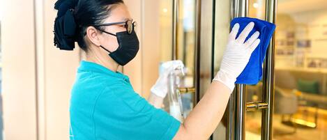 A person cleaning a glass door with a cloth and spray bottle.