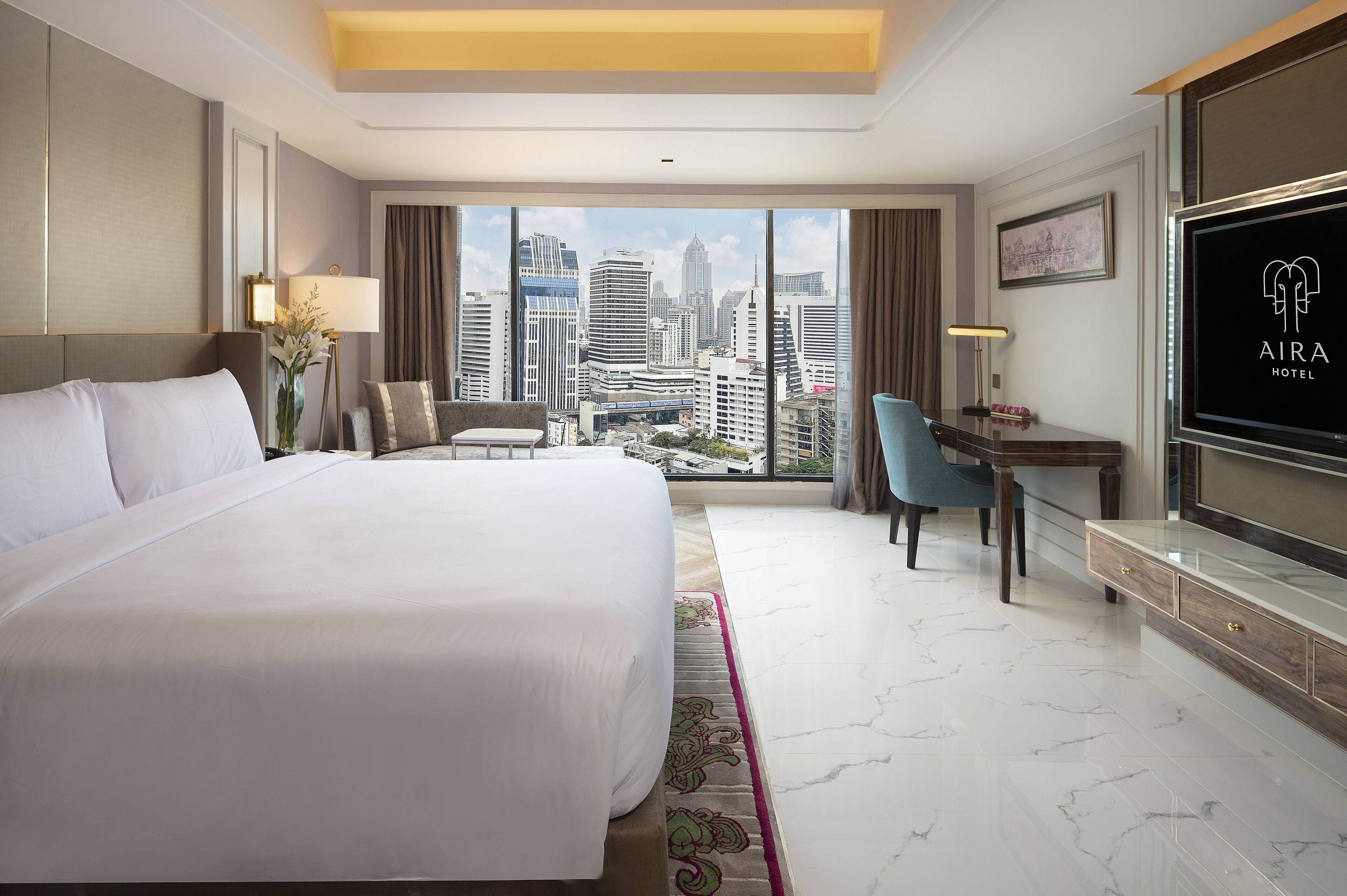 A hotel room with a large bed, a desk, a chair, a TV, and a city view.