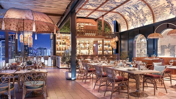 Ein Restaurant mit hoher Decke, aufwendiger Deckenverzierungen und Blick auf die Stadt.