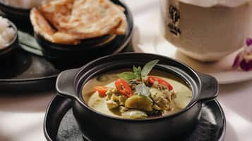 Une table avec un bol de soupe, du pain plat et un récipient fermé, qui contient probablement un dessert ou une boisson.