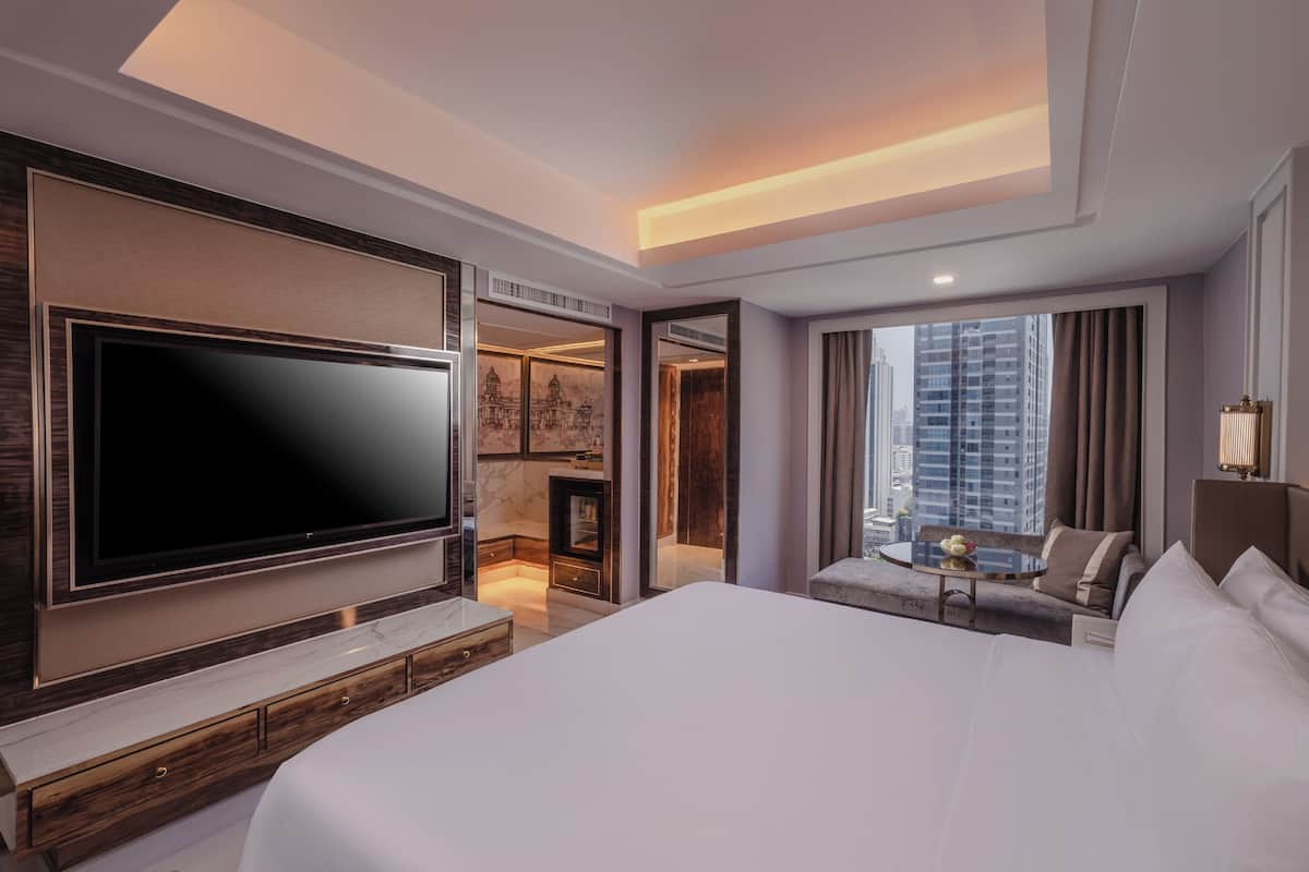 Una habitación de hotel moderna con una cama grande, un televisor de pantalla plana, una chimenea, un área de descanso con una mesa y vistas a la ciudad.