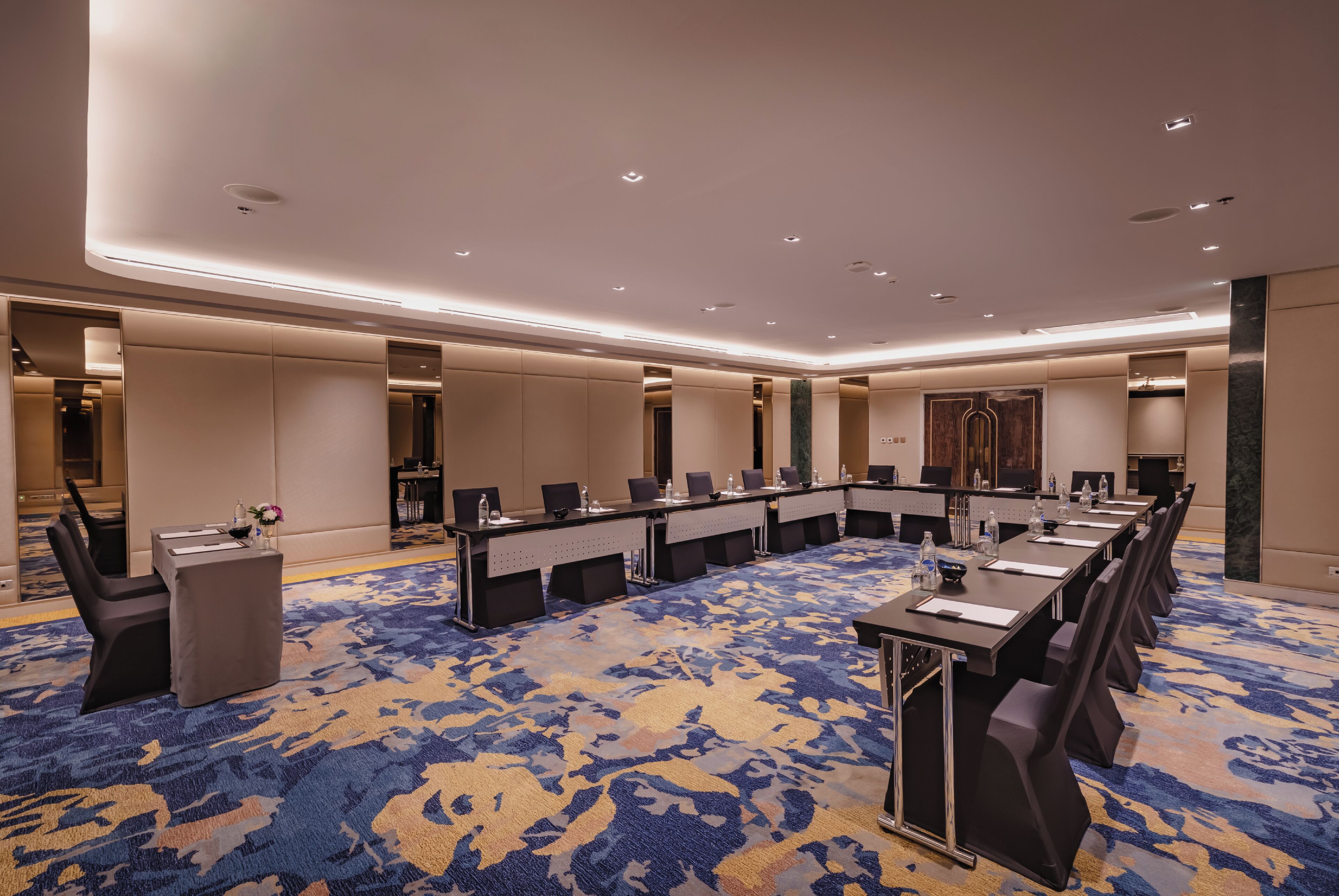 A conference room with a long table, multiple chairs, and a carpeted floor.