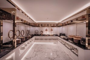 Une salle de bain moderne avec un sol en marbre, plusieurs lavabos et une variété d’articles de toilette et de serviettes.