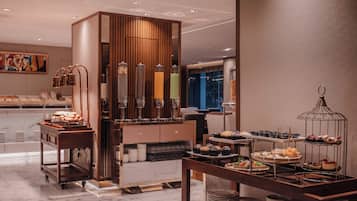A modern hotel room with a marble floor, a wooden minibar, and a variety of food and drink options on display.