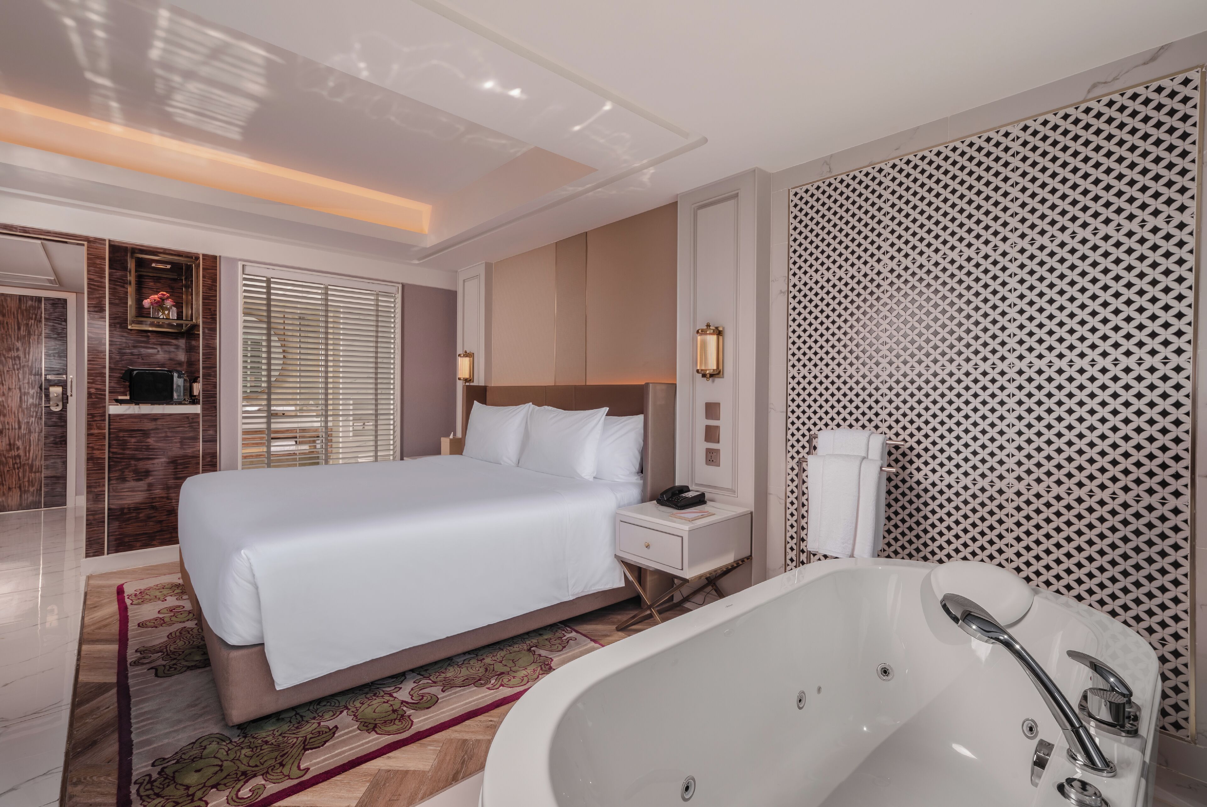 A modern hotel room with a large bed, a separate bathroom with a bathtub, and a walk-in closet.