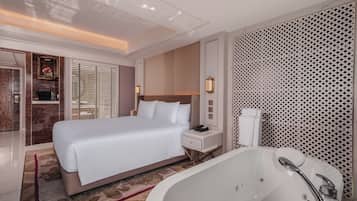 A modern hotel room with a large bed, a separate bathroom with a bathtub, and a walk-in closet.