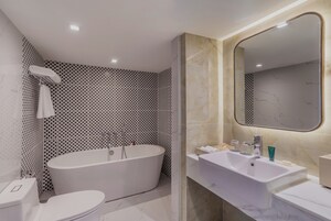 Ένα σύγχρονο μπάνιο με μια αυτόνομη μπανιέρα, έναν νιπτήρα με πάγκο και έναν μεγάλο καθρέφτη.