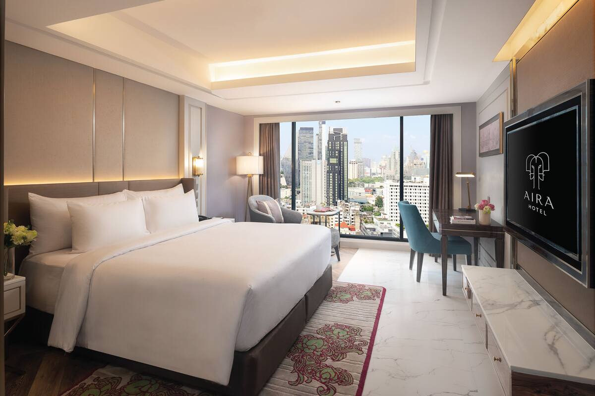 Habitación de hotel moderna con una cama grande, un escritorio, un televisor y vistas a la ciudad.