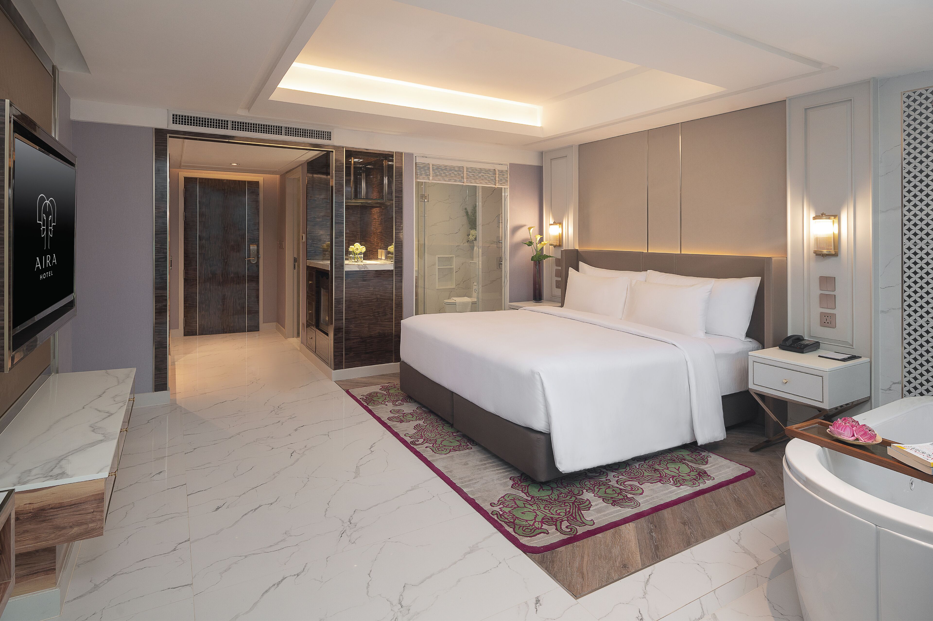A modern hotel room with a large bed, a separate bathroom, a TV, and a walk-in closet.