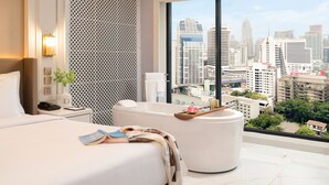 Ein modernes Hotelzimmer mit einem großen Bett, einer Badewanne und Blick auf die Stadt.