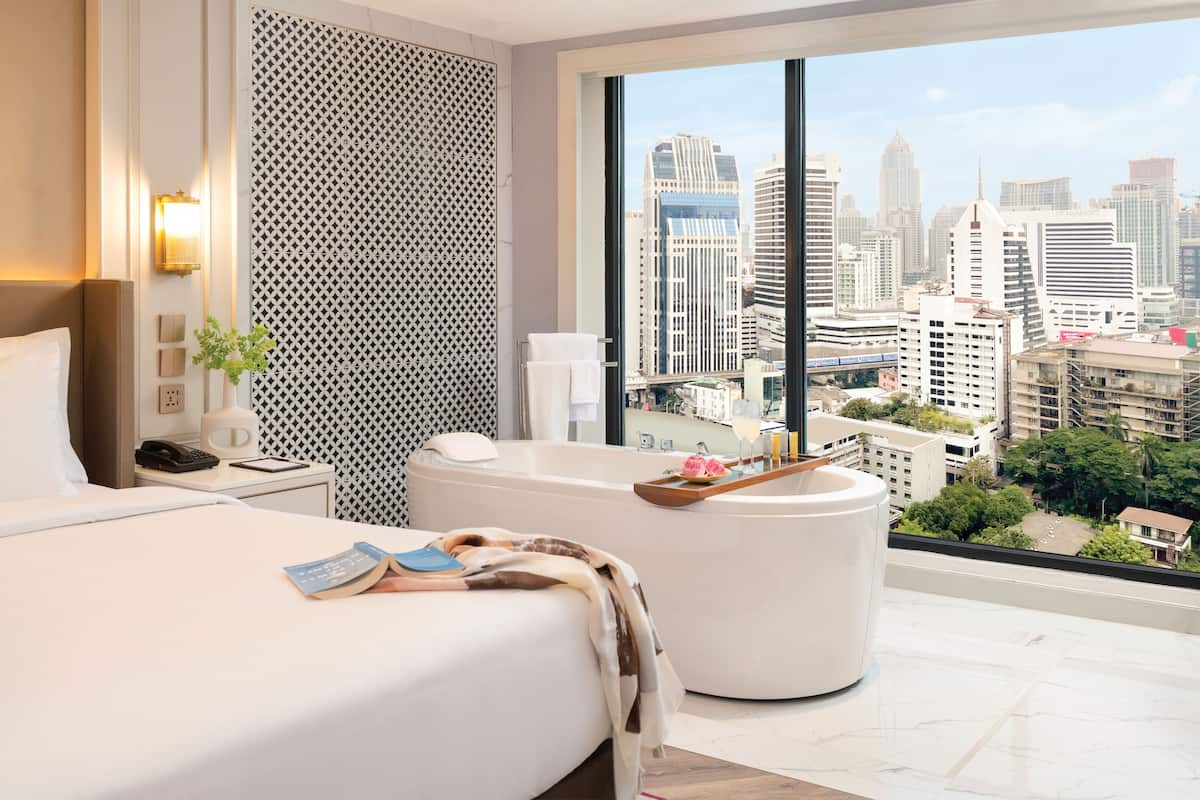 Una habitación de hotel moderna con una cama grande, una bañera y vistas a la ciudad.
