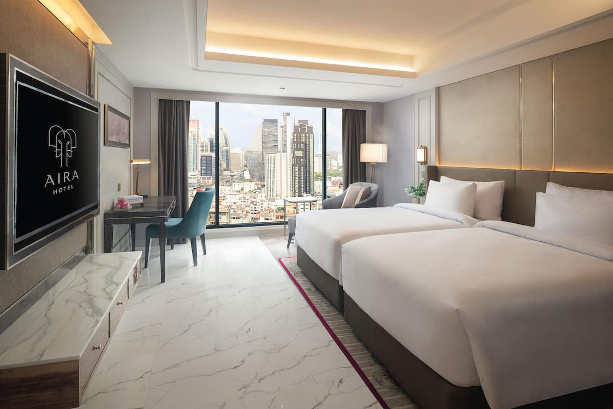 Una habitación de hotel con una cama grande, un escritorio, una silla y un televisor.