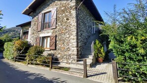 A stone house with a sloped roof, wooden shutters, and a paved entrance. - Cottage al Lago by Interhome (Gravedona)