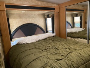 Cozy bedroom with a single bed, full-length mirror, and window with blinds.