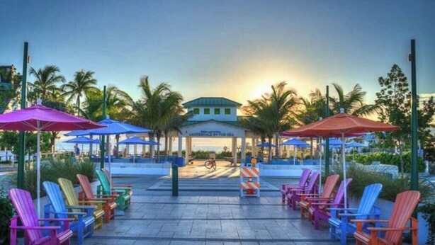 A resort with colorful Adirondack chairs, umbrellas, and a building with a sign reading "LAURENWOOD BEACH CLUB".