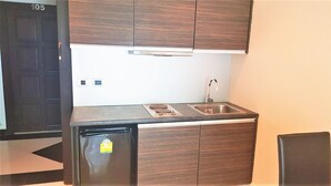 A compact kitchen with a refrigerator, sink, and wooden cabinets. - Park Lane Resort Jomtien With Large Lagoon Swimming Pool (Pattaya)