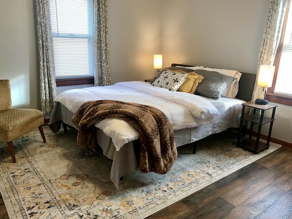 A neatly made bed with a brown blanket, a bedside lamp, and a patterned rug.