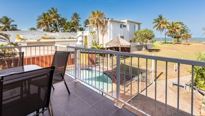 A balcony with a pool, palm trees, and a view of the sea. - Driftwood on the Beach - Sea View Unit 10 (Yeppoon)
