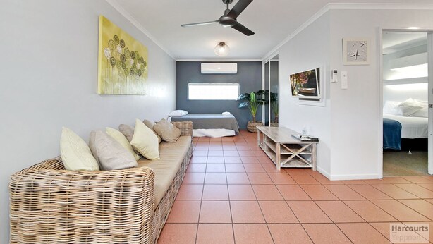 Een moderne woonkamer met een bank, een eettafel en een plafondventilator.