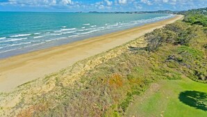 Een strand met een zandstrand en schaarse begroeiing.